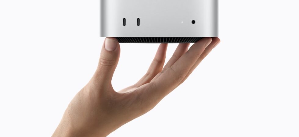 Ruka držící stříbrný Mac mini s porty na přední straně